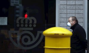 Una hombre protegido con mascarilla espera entrar en Correos, en Bilbao. - EFE
