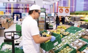 Un empleado repone fruta en un supermercado