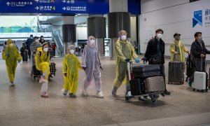 Viajeros llegan al aeropuerto internacional de Hong Kong provistos de trajes de aislamiento y mascarillas. /EFE