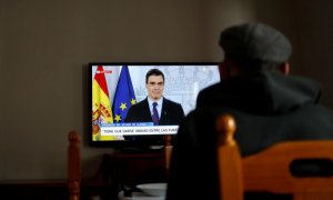 Un anciano ve en la televisión una rueda de prensa de Pedro Sánchez sobre el coronavirus. / JON NAZCA (REUTERS)