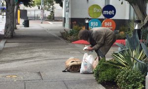 Un indigente de mediana edad comiendo en mitad de una céntrica calle de Los Ángeles. / Aitana Vargas