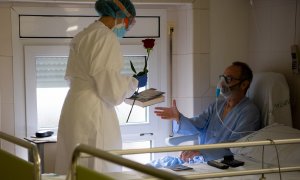 Una professional de l'Hospital Clínic lliura a un pacient ingressat una rosa i un llibre per Sant Jordi, en la pandèmia de coronavirus. Francisco Ávila / Hospital Clínic