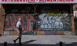 Un hombre protegido con mascarilla camina ante un comercio cerrado en una céntrica calle de Sevilla, durante el confinamiento decretado en el Estado de Alarma debido a la crisis sanitaria de la covid-19. EFE/Julio Muñoz
