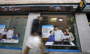 Un hombre pasa por delante de una oficina de Caixabank, en Madrid. EFE/Juan Carlos Hidalgo