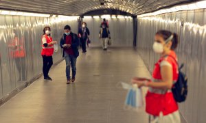 GRAFCAT5817. BARCELONA, 04/05/2020.- Voluntarias de la Cruz Roja reparte mascarillas en el Metro de Barcelona, este lunes, primer día en el que el uso de mascarillas en el transporte público es obligatorio, en el inicio de la fase 0 del plan de desescalad