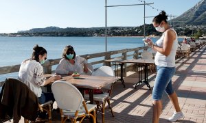 Una camarera atiende a dos clientas en una terraza en la localidad Alicantina de Denia, uno de los territorios de España que comienza la Fase 1.EFE/ Juan Carlos Cárdenas