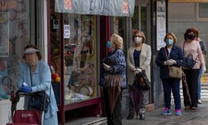 12/05/2020.- Varias mujeres con mascarillas hacen cola ante una mercería en el barrio de Triana de Sevilla, hoy martes en el segundo día de la fase 1 de desescalada en la que diferentes actividades han podido retomar su actividad desde que se inició el es