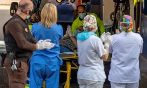 Un paciente que baja de una ambulancia participa en el apluaso al personal sanitario y de seguridad del hospital Virgen de la Salud de Toledo este domingo. Los sanitarios han agradecido el apoyo de los ciudadanos que se han acercado convocados a través de