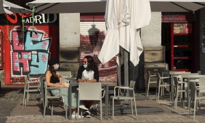 Dos personas esperan su consumición en una terraza de un bar de la Plaza Mayor en Madrid este lunes, donde comienza la fase 1 en la que la reapertura de las terrazas de los bares a un 50 % de su aforo y el acceso a los grandes parques son dos las principa