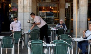 25/05/2020.- Un camarero sirve a los clientes en su bar de la Plaza Mayor de Salamanca este lunes durante el primer día de la fase 1 en la ciudad cuando las terrazas de los bares tienen su capacidad al 50 % y se permite el acceso a los grandes parques. EF