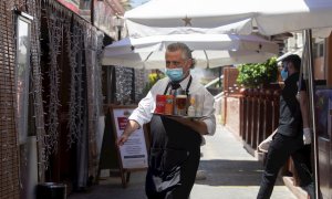 27/05/2020.- Un camarero lleva su pedido a unos clientes a una de las terrazas del Puerto Olímpico de Barcelona. / EFE