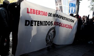 Jóvenes integrantes del Movimiento Antirrepresivo de Madrid con una pancarta en la que se lee, `Libertad de Manifestación, Detenidos Absolución´, concentrados frente a los juzgados de Plaza de Castilla en apoyo a los detenidos en el centro de Madrid duran