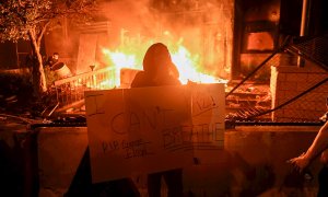 Un manifestante sostiene un cartel mientras se quema la comisaria de Minneapolis durante las protestas por el arresto de George Floyd. EFE / CRAIG LASSIG