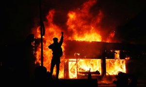 Un manifestante delante de una edificio ardiendo durante los disturbios desatados en Minesota tras la muerte de George Floyd, un ciudadano negro, a manos de la policía.- REUTERS