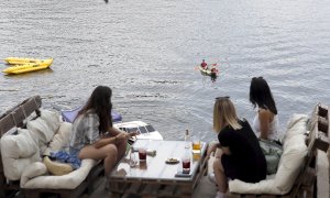 Varias personas disfrutan del aperitivo en el chiringuito La Martuka, hoy domingo en el madrileño pantano de San Juan, en un día soleado y con altas temperaturas. EFE/J.J. Guillén