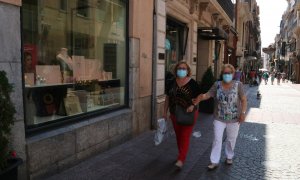 Pla general de dues dones amb mascareta i una bossa de la compra al carrer Monterols de Reus. Imatge del 28 de maig del 2020 (Horitzontal).. Mar Rovira | ACN