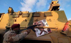 Un miembro del Ejército Nacional de Libia (LNA) comandado por Khalifa Haftar, apunta su arma a la imagen del presidente turco Tayyip Erdogan colgado de un vehículo blindado militar turco en Benghazi, Libia. REUTERS / Esam Omran Al-Fetori