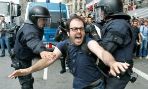 Dos policías intentan sujetar a una de las personas concentradas en la plaza Cataluña de Barcelona. ANDREU DALMAU (EFE)