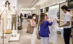 Dos clientas se desinfectan las manos con gel hidroalcohólico a la entrada de una tienda de ropa en Valencia.| Rober Solsona.  Europa Press