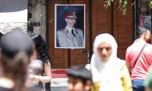 Varias personas pasan por una calle de Damasco, cerca de un retrato del presidente Sirio, Bashar al-Assad. AFP/LOUAI BESHARA
