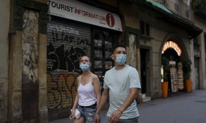 Una pareja pasa por delante de una oficina de turismo cerrada en Barcelona