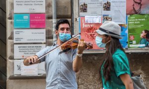 Un músico se protege con mascarilla mientras actúa en una calle en Palma de Mallorca | EFE