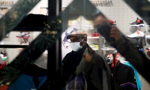 Un hombre protegido con una mascarilla realiza compras en los Campos Elíseos en París | EFE