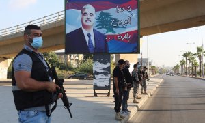 Miembros de las fuerzas de seguridad montan guardia en Sidón, al sur del Líbano, cerca de un cartel con la imagen del exprimer ministro libanés, Rafik al-Hariri, quien murió en un atentado suicida en 2005. REUTERS / Aziz Taher