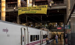 Activistas de Greenpeace han desplegado esta mañana una pancarta sobre las vías de Atocha para denunciar la falta de trenes en un verano marcado por la crisis de la covid-19. Bajo el texto "Ábalos: faltan trenes, sobran aviones". EFE/Pablo Blázquez