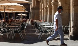 Un hombre con mascarilla pasa frente a una terraza de un restaurante de la plaza mayor de Salamanca, este miércoles. | EFE