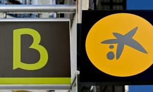 Los logos de Bankia y de Caixabak, en sendas sucursales de los bancos en proceso de fusión. AFP