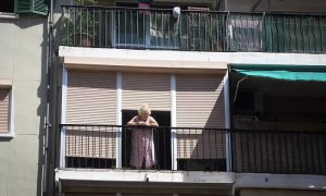 Una mujer sale a la terraza en uno de los barrios confinados / Getty Images