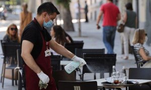 Un camarero desinfecta una mesa de una terraza / EFE