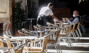 Un camarero atiende a un cliente, este miércoles, en un local de la Plaza Real de Barcelona. /EFE