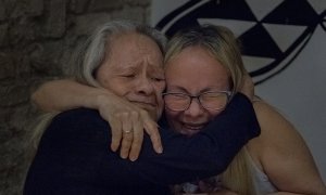 Dos mujeres se abrazan, madre e hija, ante la incertidumbre en el futuro que les genera el cierre del albergue. EVA PAREY.