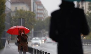 Dos transeúntes caminan entre la lluvia por las calles del centro de Madrid esta mañana de martes. EFE/ Mariscal