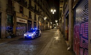 Una patrulla de la Guardia Urbana recorre la Calle Ferran de Barcelona durante el segundo día de la aplicación del "toque de queda" en vigor desde el pasado domingo.