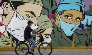 Un hombre pasa en bicicleta frente a un mural en Ciudad Juárez.