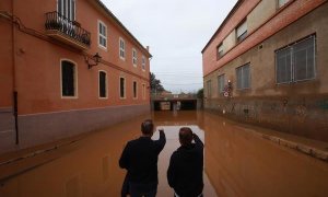 Dos hombres observan el acceso a un paso inferior de la vía ferroviaria inundado por el temporal que afectó en la localidad valenciana de Carcaixent.