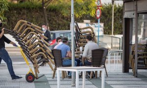 Camareros de un bar de Mairena del Aljarafe(Sevilla) recogen el mobiliario para proceder al cierre antes de las seis de la tarde