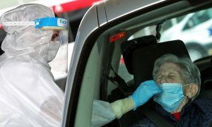 Una sanitaria protegida con EPI toma una muestra para una prueba PCR frente al hospital de Gandía.