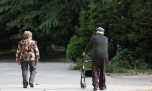 Una mujer y un hombre de edad avanzada con andador paseando. En Madrid, (España).