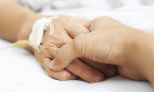 Una persona coge la mano a un paciente.