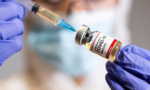 Una sanitaria sostiene una muestra donde se lee "Vacuna covid-19"
