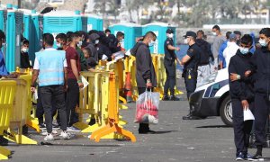 Varios inmigrantes llegados la pasada madrugada esperan este miércoles en el muelle de Arguineguín (Gran Canaria) a que les tomen las huellas dactilares y la filiación.