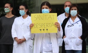 Una enfermera con una pancarta defendiendo la salud pública durante una movilización ante la Delegación de la Generalitat a Girona. ACN/Aleix Freixas