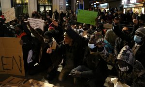 Persones assegudes i amb el puny alçat durant el minut de silenci a la Plaça de la Vila de Badalona.