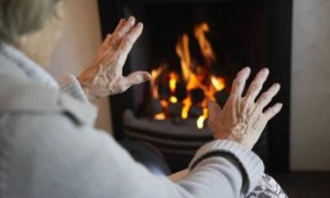 Una mujer calienta sus manos en una chimenea.