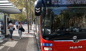 Un bus aturat a la plaça Universitat amb usuaris a la parada.