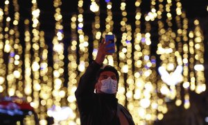 Una persona se fotografía con las luces de navidad del centro de Barcelona.